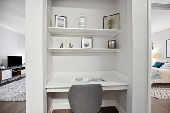A white desk with a grey chair in a room with a white wall.